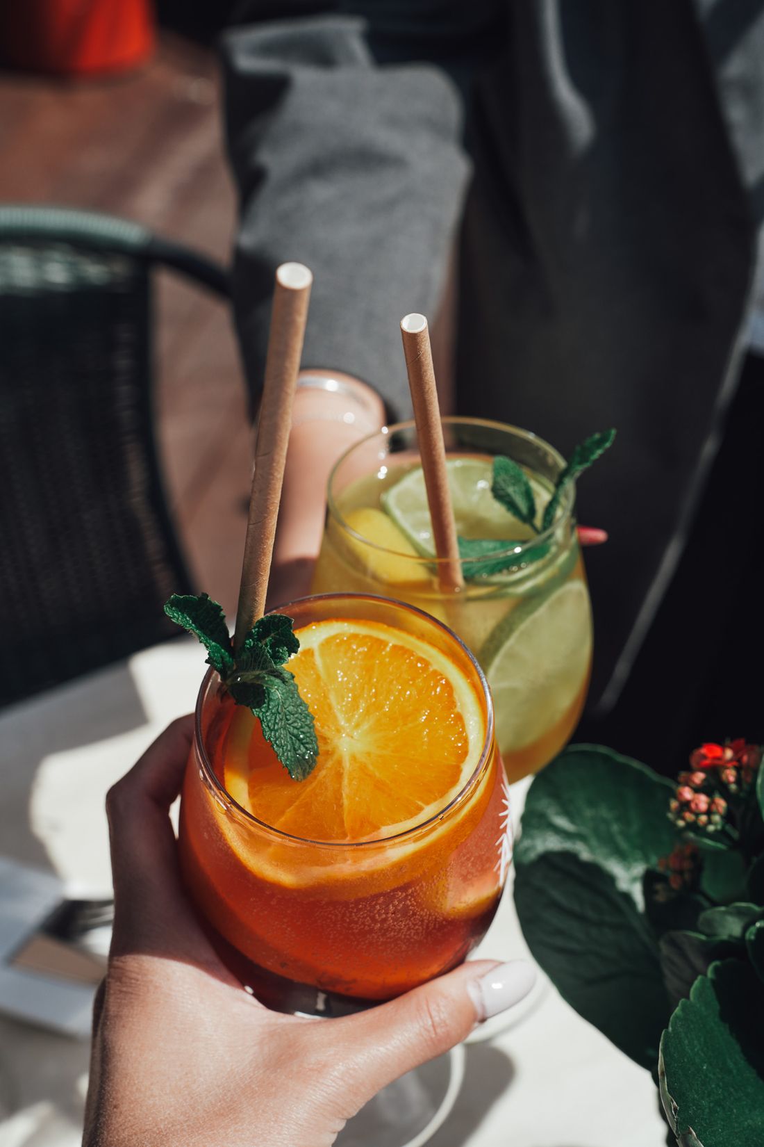 Deux cocktails frais aux tranches d'orange et à la menthe, servis avec des pailles en papier
